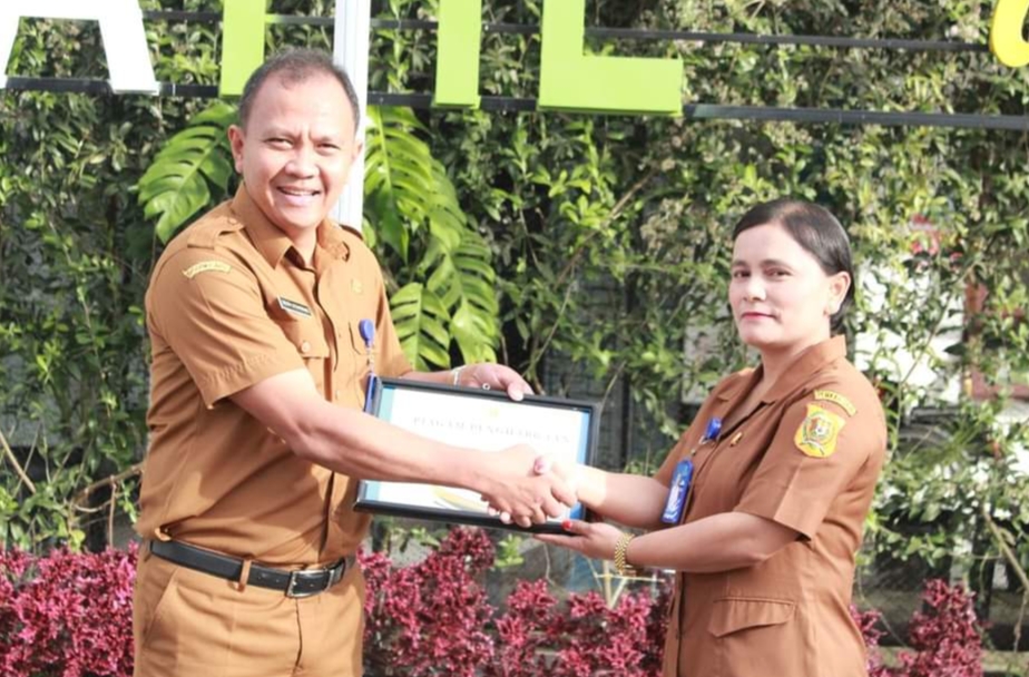 Kadis Dukcapil Dairi Deddy Situmorang serahkan piagam kepada pegawai terbaik Sedima Sianturi.(foto/ist)